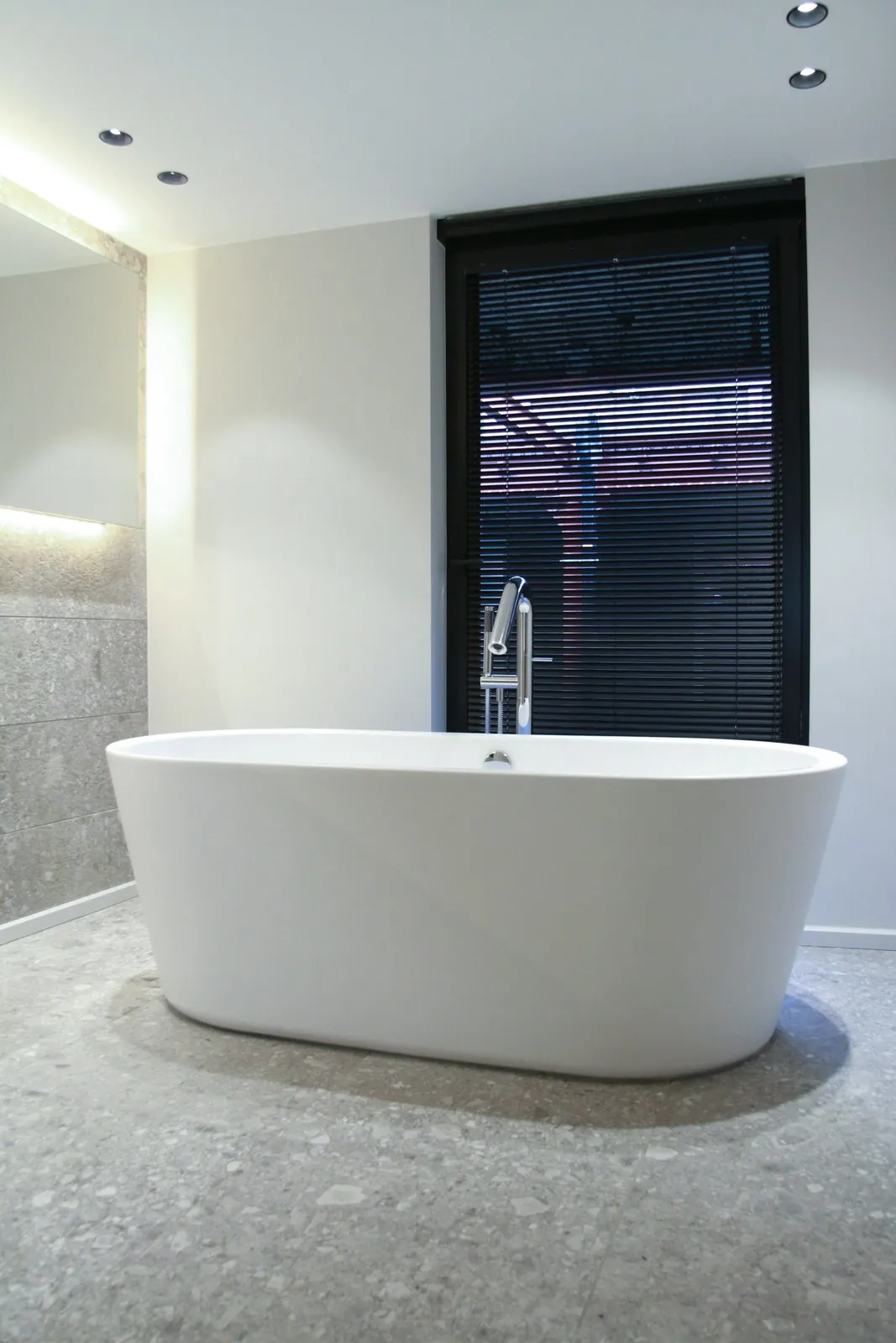 Bañera exenta blanca en baño con suelo de terrazo
