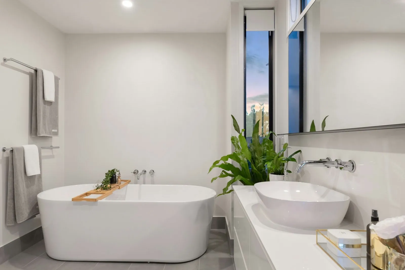 Baño blanco con bañera exenta, lavabo sobre encimera y plantas
