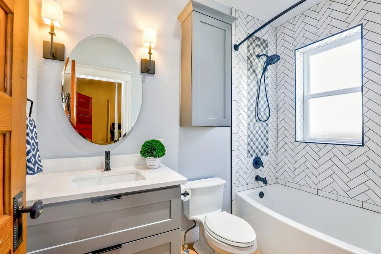 Salle de bain avec baignoire, carrelage blanc en chevrons et miroir ovale