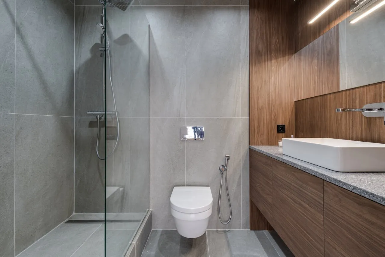 Baño gris con ducha a ras de suelo e inodoro suspendido