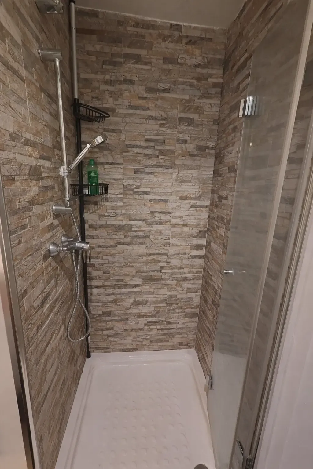 Douche avec receveur blanc, paroi coulissante et parement pierre