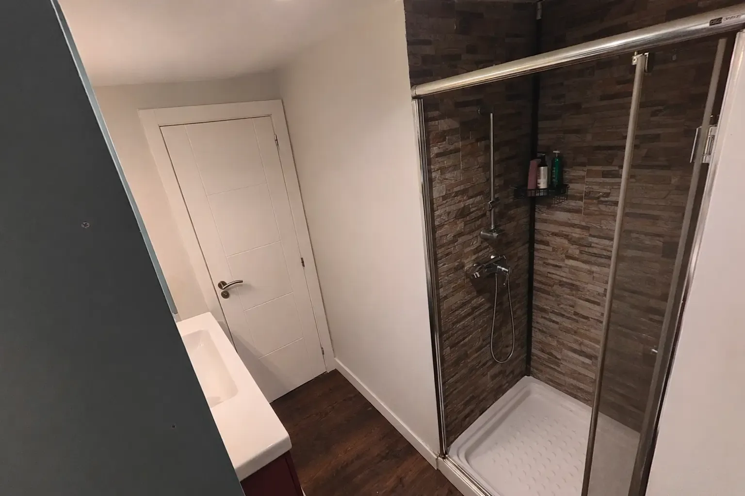 Douche avec paroi coulissante et murs en parement pierre, vue de l’entrée