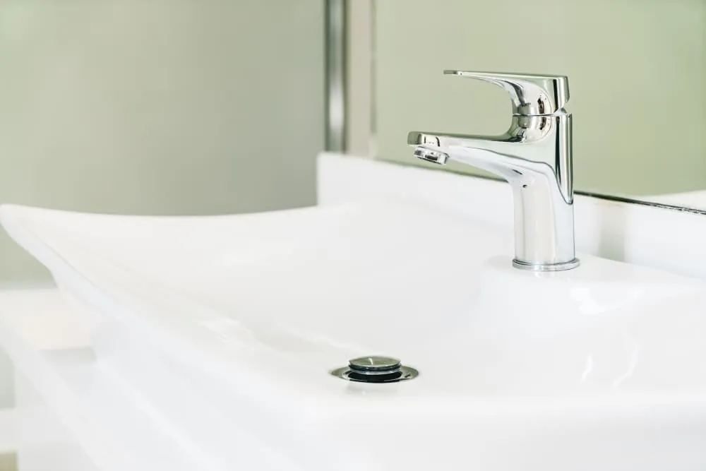 Grifo monomando cromado sobre lavabo blanco