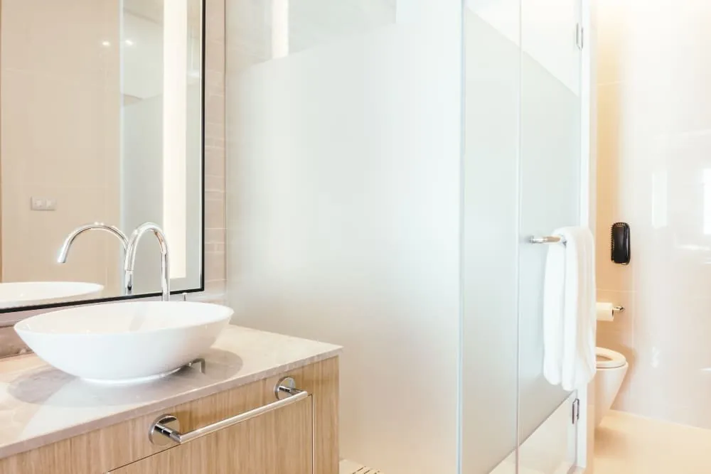 Lavabo sobre encimera de madera y mampara de vidrio esmerilado