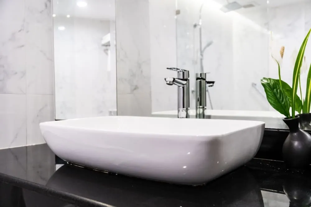 Lavabo sobre encimera negra con grifo cromado